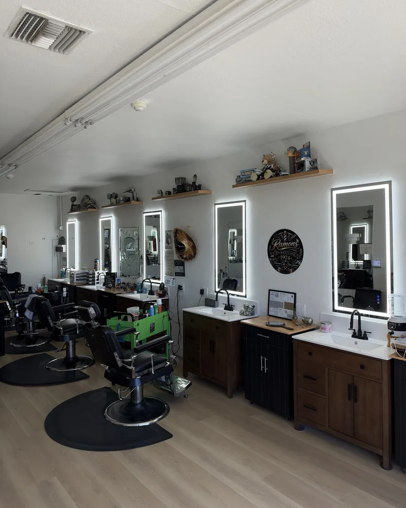 A row of barber chairs and backlit mirrors along the wall inside Ramon’s Barber Shop in Covina